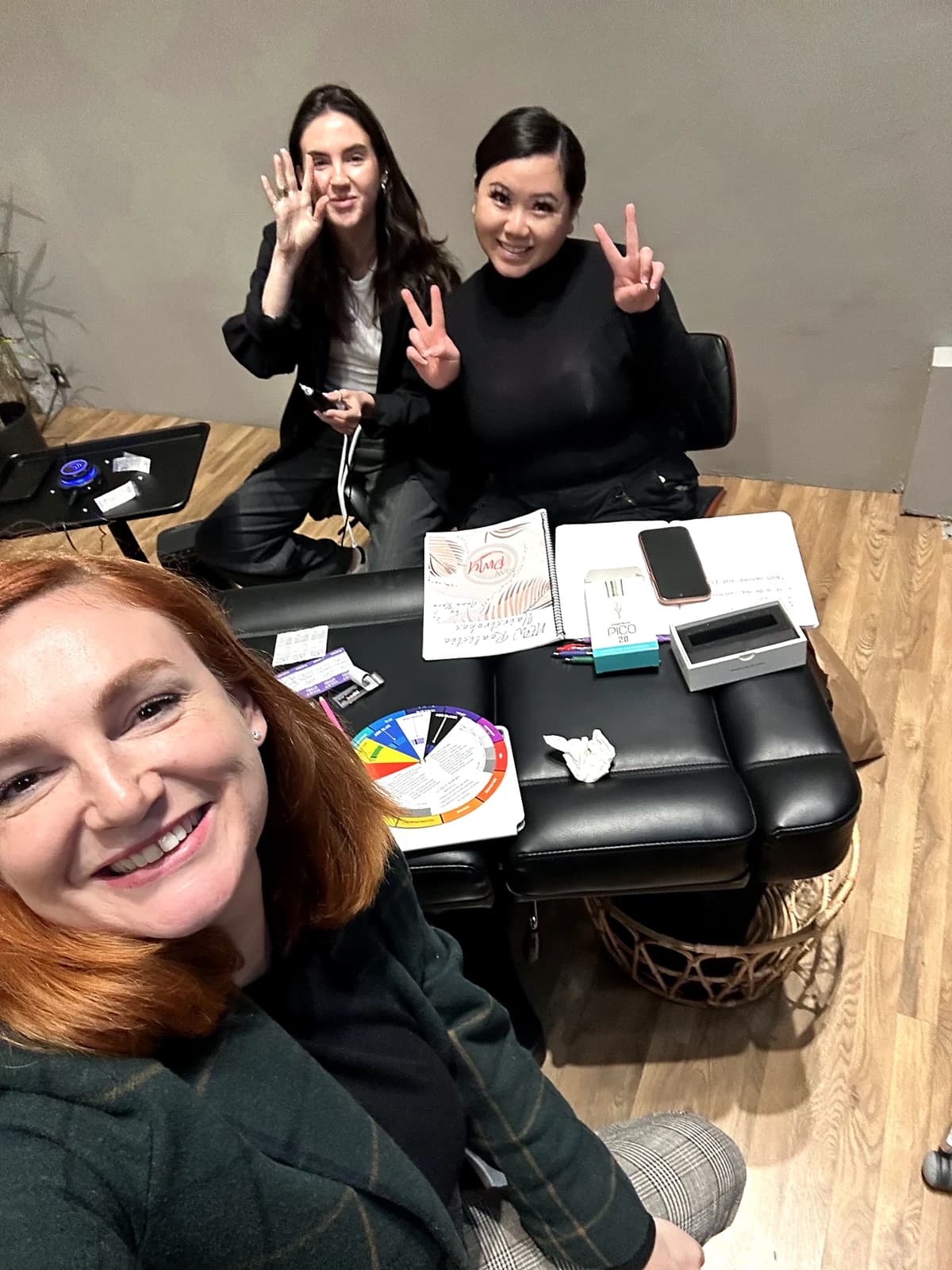 Anna and two Academy team members at a table with the course workbook, color wheel and training supplies