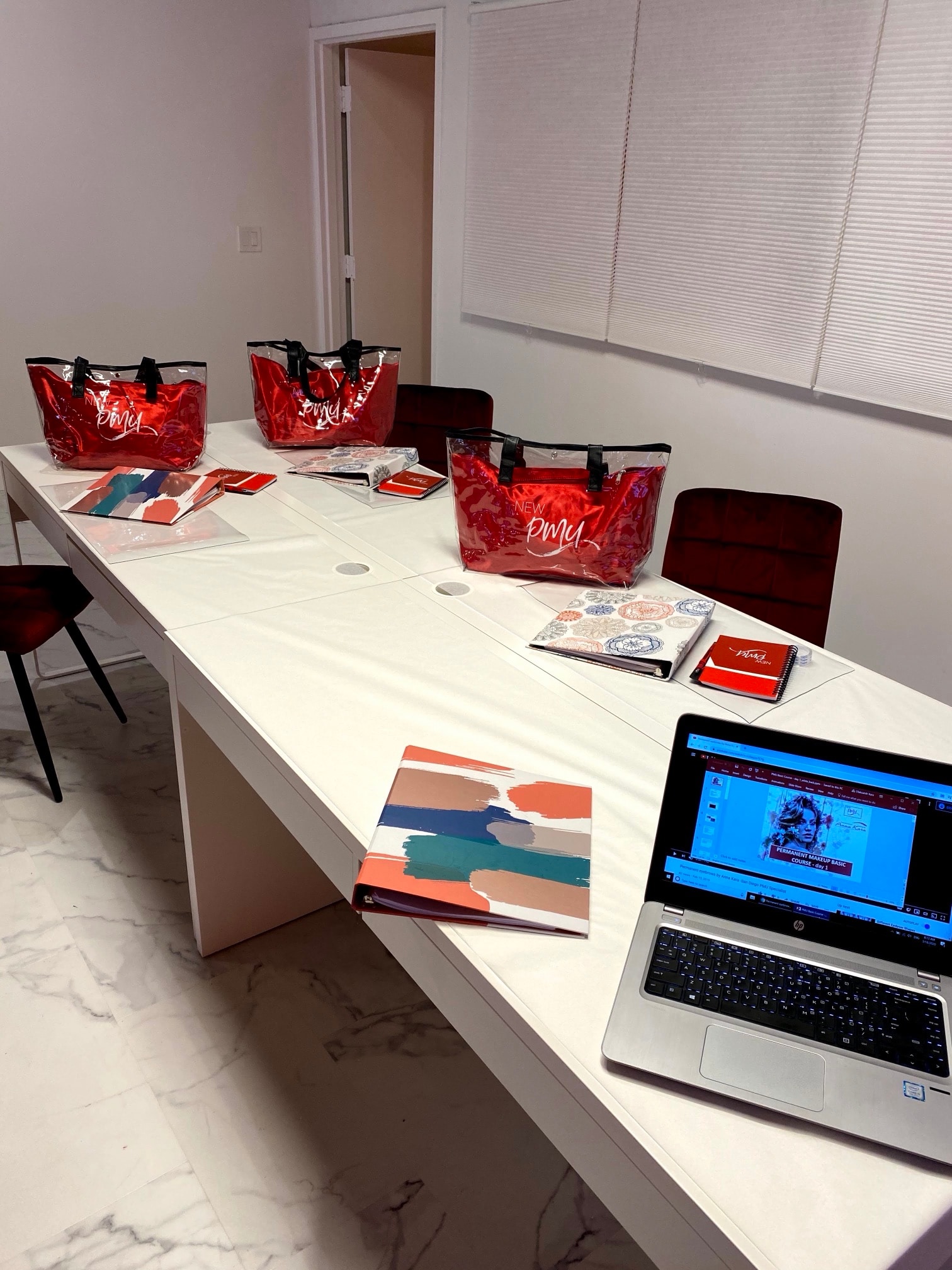 Table with New PMU bags, binders and notebooks and a laptop showing a Basic course slide
