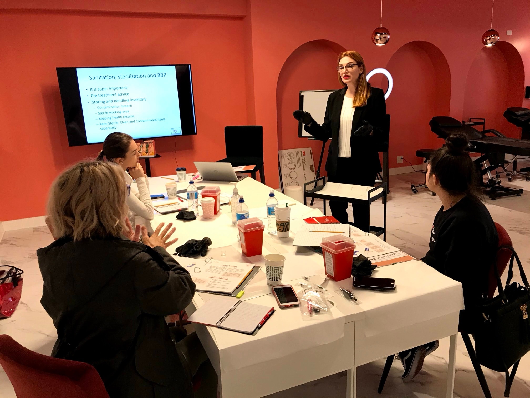 Anna in gloves presenting a sanitation and sterilization slide to students seated at a table