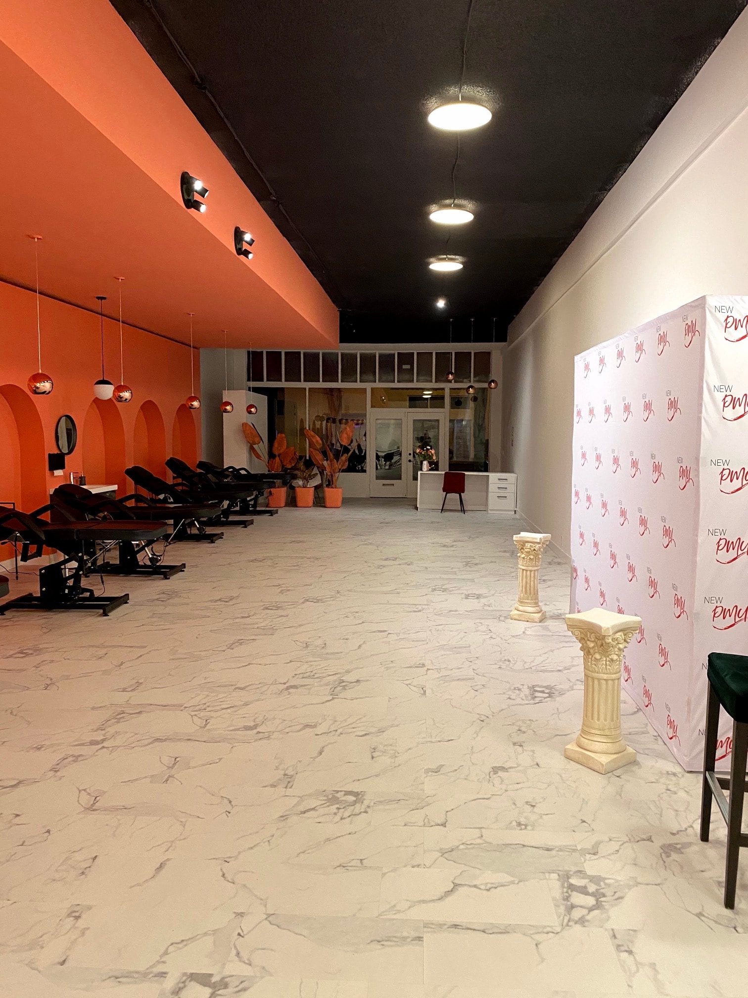 The hall with a New PMU branded backdrop, treatment beds along the coral wall