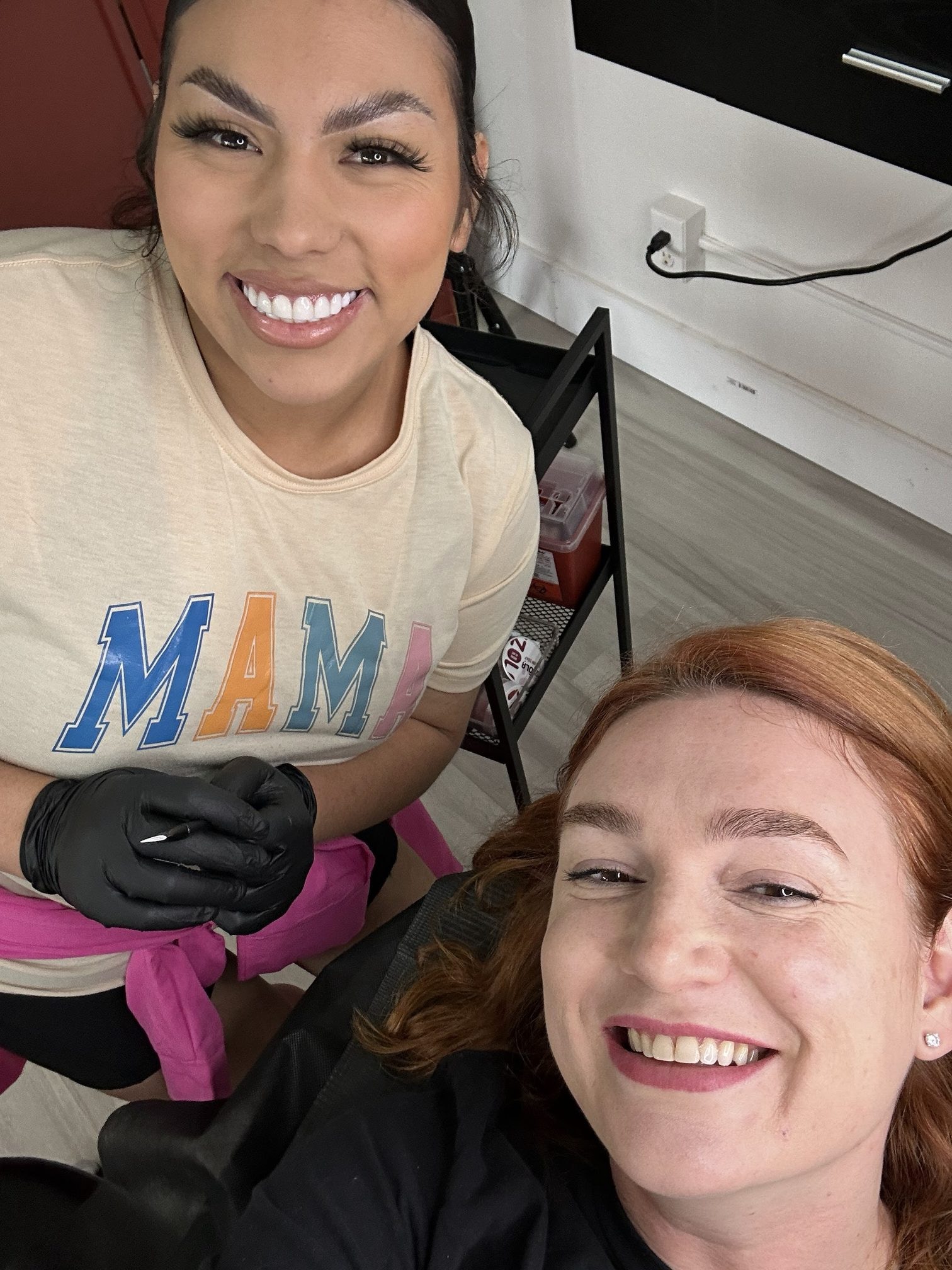 Anna Kara smiling in the treatment chair next to a student in black gloves