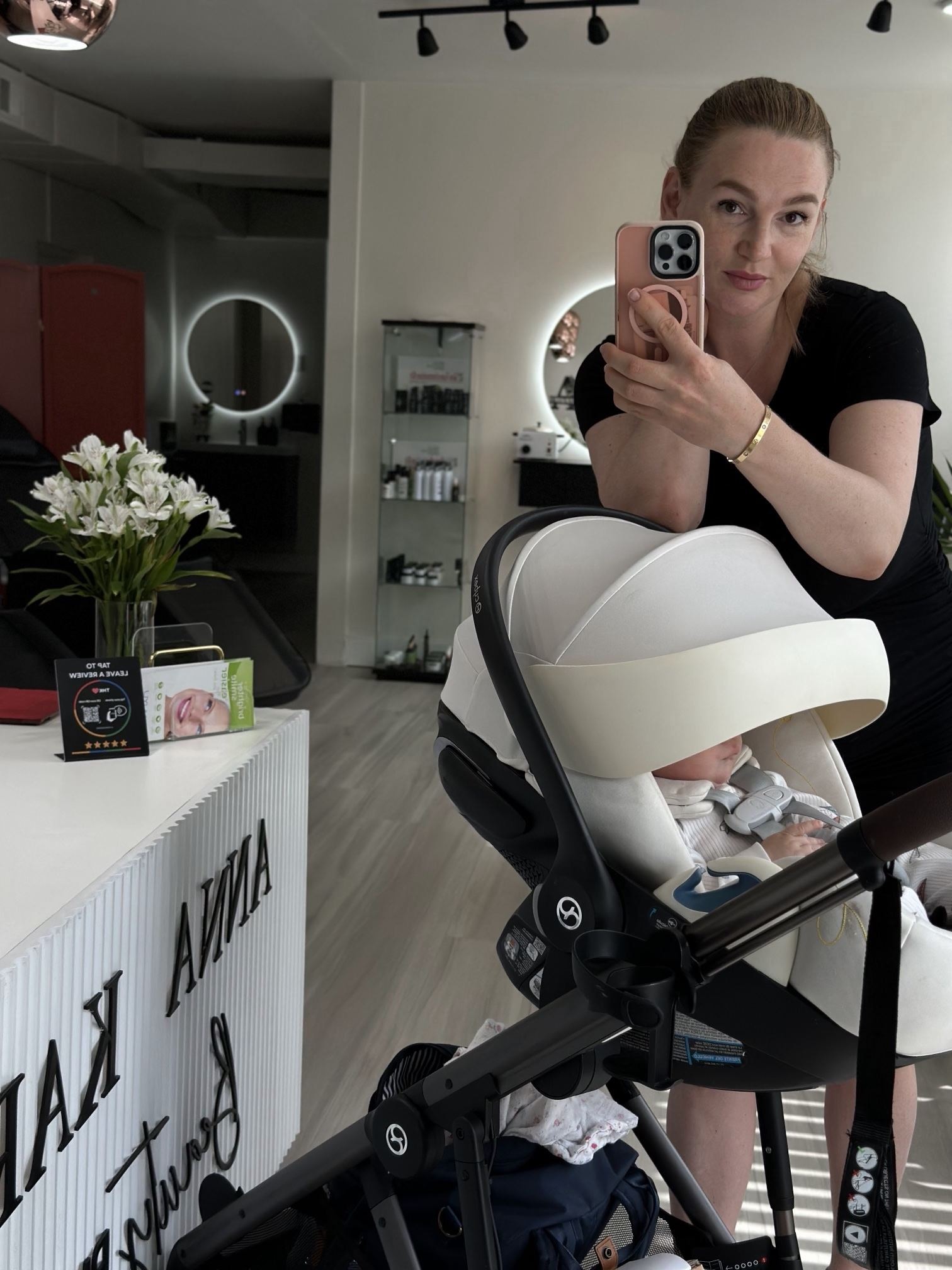 Anna taking a mirror selfie in the studio next to a baby car seat