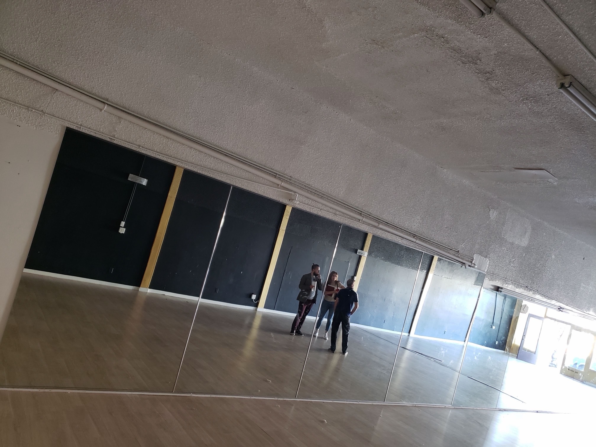 Empty dance studio with mirrors along the wall, before the renovation