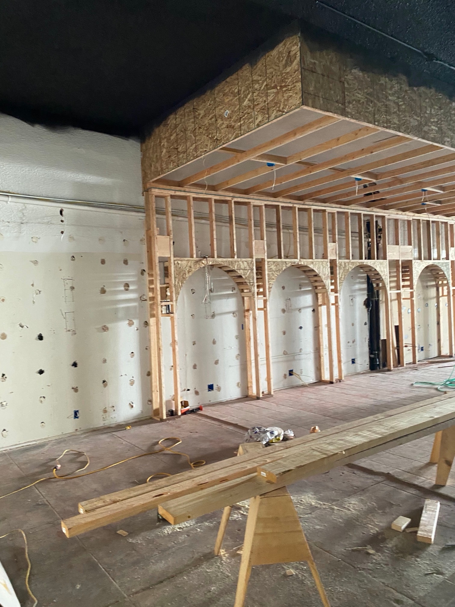 Wooden frame of arched niches along a bare wall during the renovation