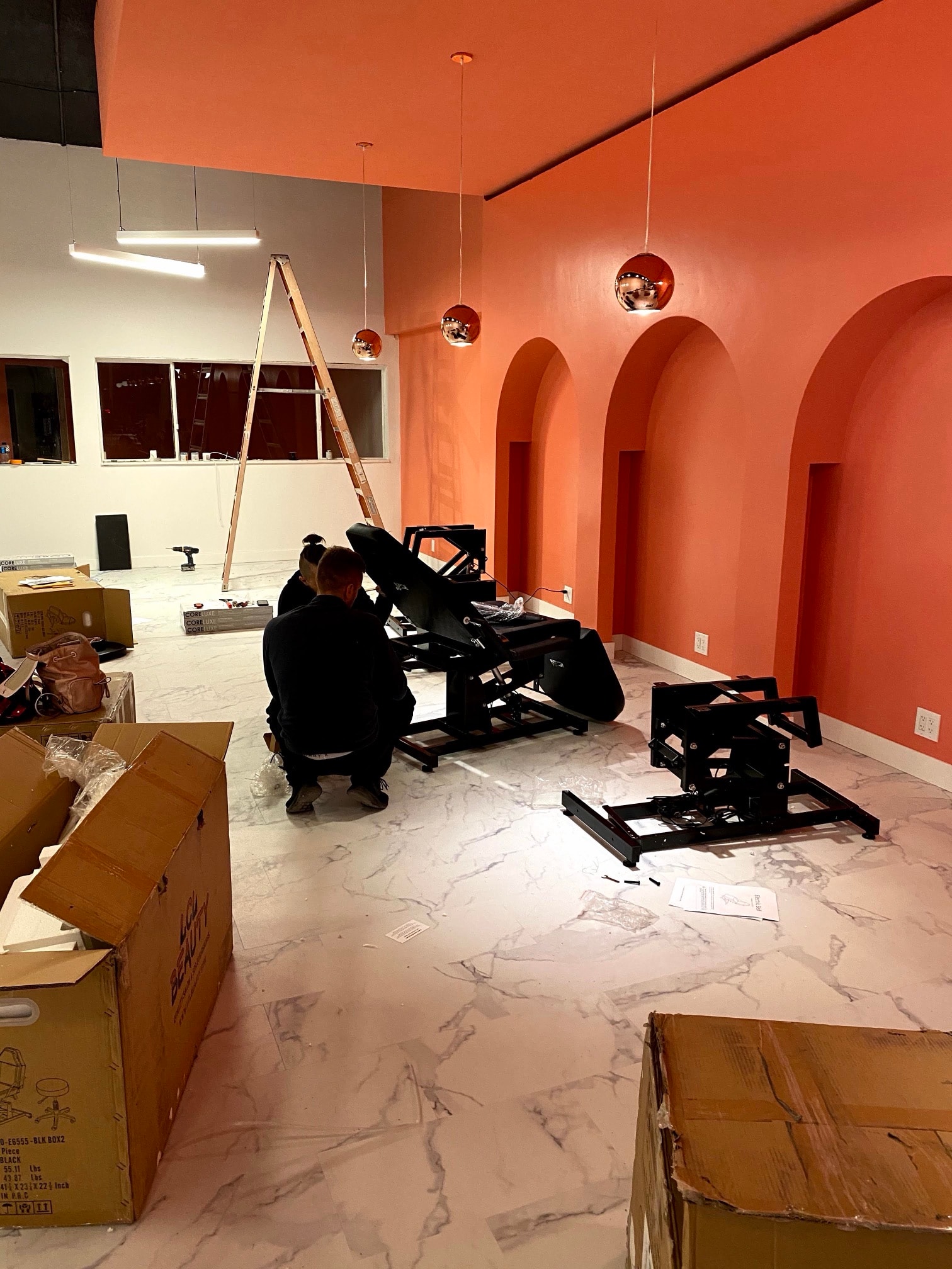 Two people assembling treatment beds in front of coral arched niches